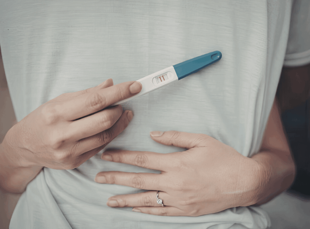 Paar umarmt sich und Frau hat Schwangerschaftstest in der Hand