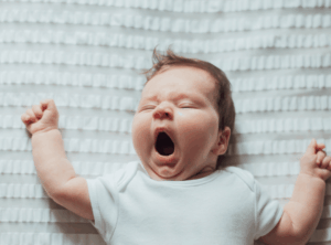 Baby liegt auf rücken und gähnt